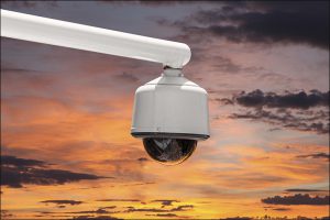 Outdoor security camera isolated with sunset sky.